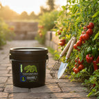 A 25 lb black plastic bucket of Flower Republic Channel 1 fertilizer in a vegetable garden. 